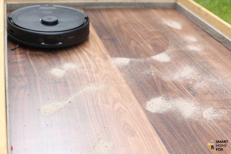 Roborock Q Revo beim Sand-Saugtest auf dem Laminat.